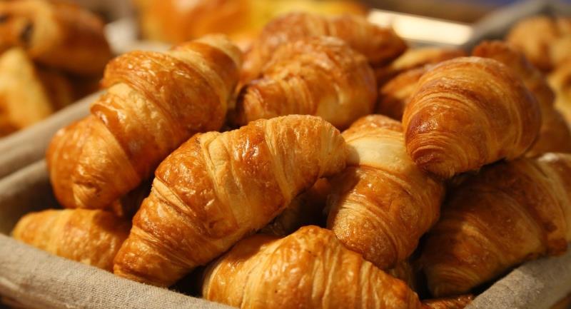 A cloth covered basket or container piled high with croissants. 