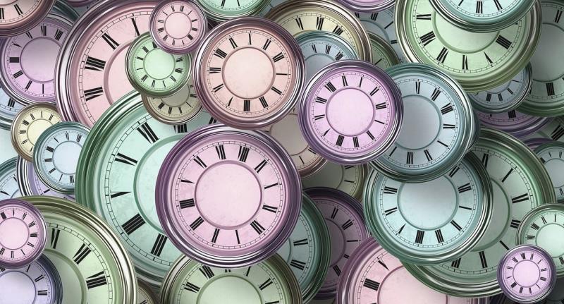 A collection of overlapping vintage clock faces with Roman numerals in pastel shades of pink, green, and blue. The clocks lack hands, emphasising timelessness and abstract representation of time.